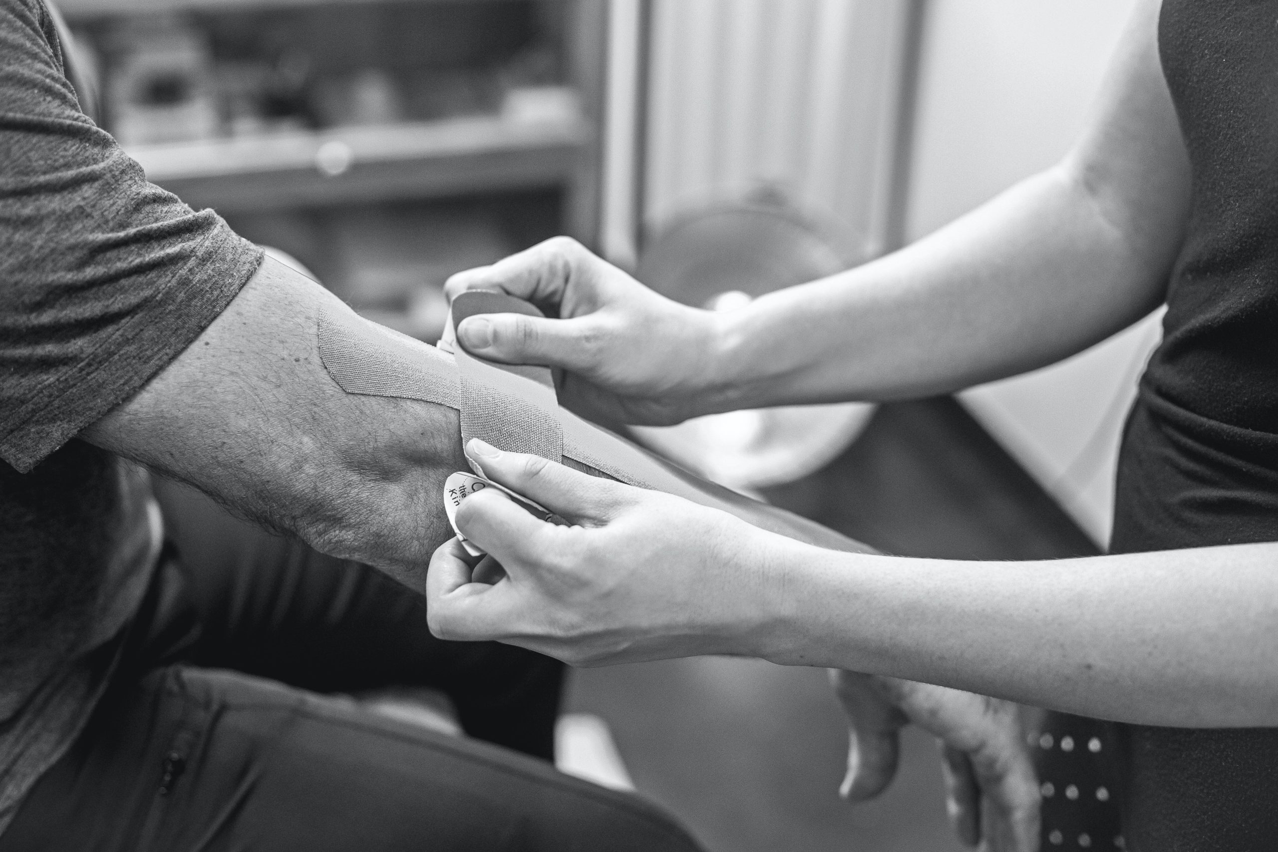 Person putting bandage on another person's arm